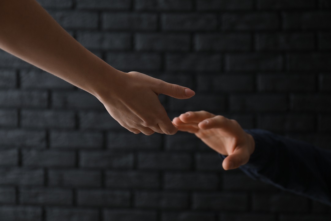 Hand reaching out to another person's hand