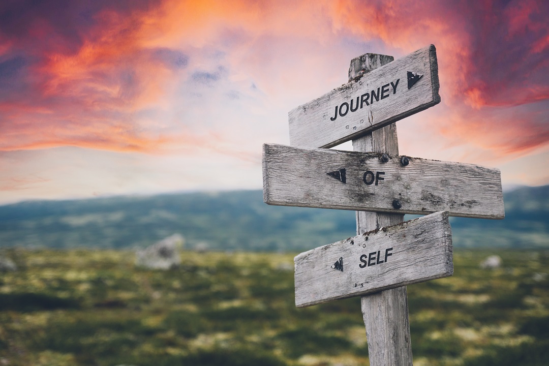 Hills and sunset sky with sign post saying Journey of Self