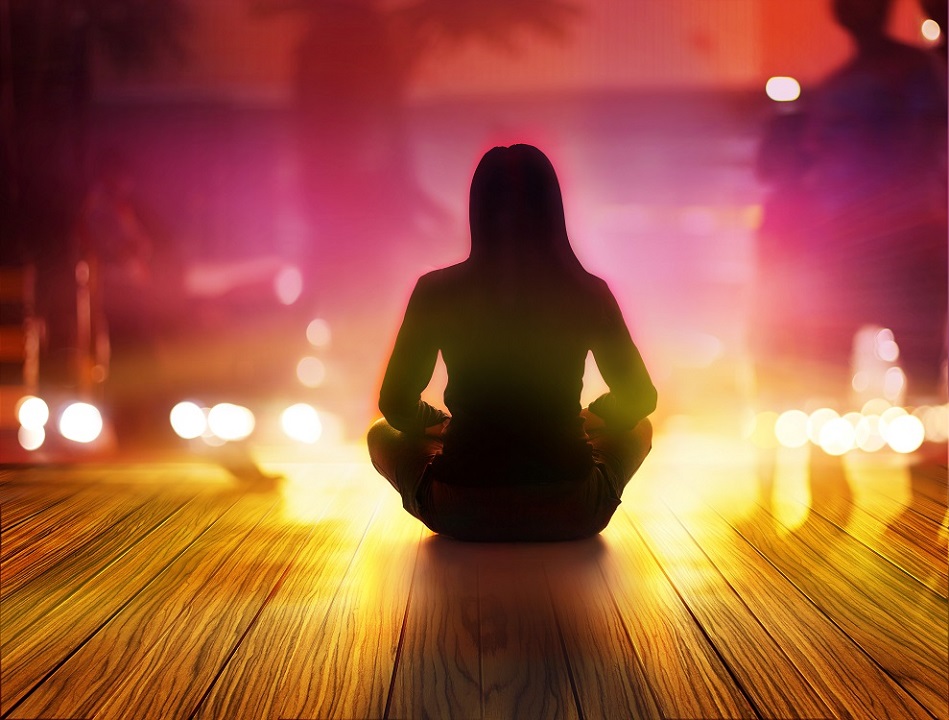 woman seated in yoga position, surrounded by lights