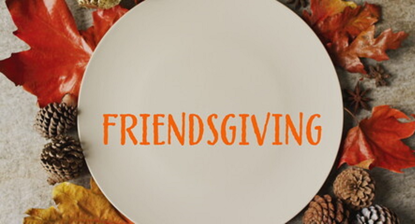 Plate with the word Friendsgiving, on a table with fall decor under it.