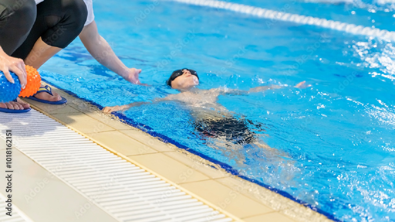 person floating in pool with swim instructor assisting