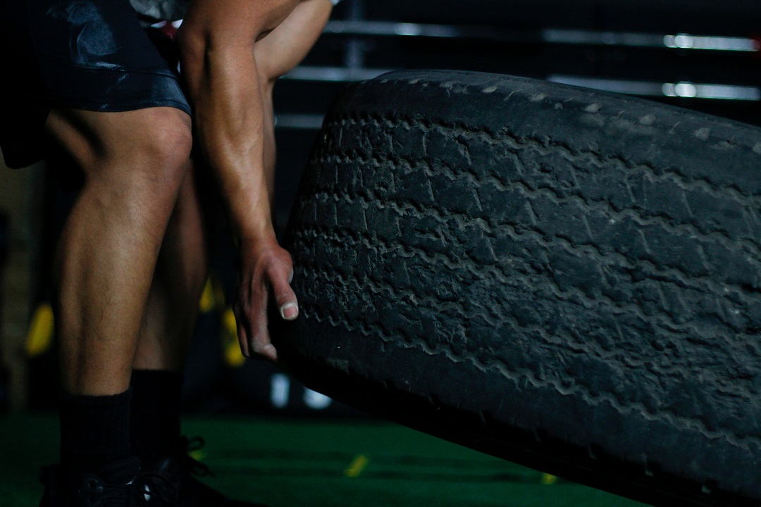 male flipping large tire in fitness center