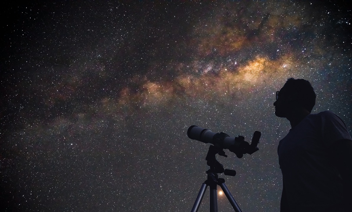 Image of night sky and a man with a telescope