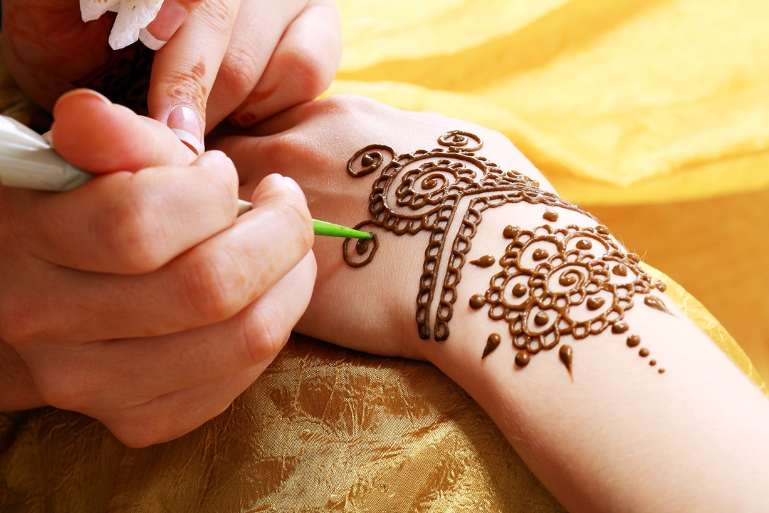 Image of person applying henna bracelet to another person's wrist