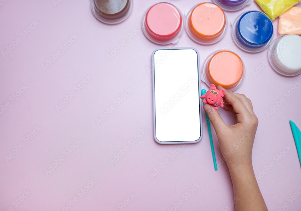Image of person holding small clay sculpture, with multiple containers of colored clay displayed on purple table