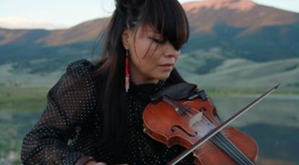 Photo image of Laura Ortman playing the violin in outdoor setting with mountains in background. Laura will be performing on Spark Night at the Zimmerli Art Museum in December.