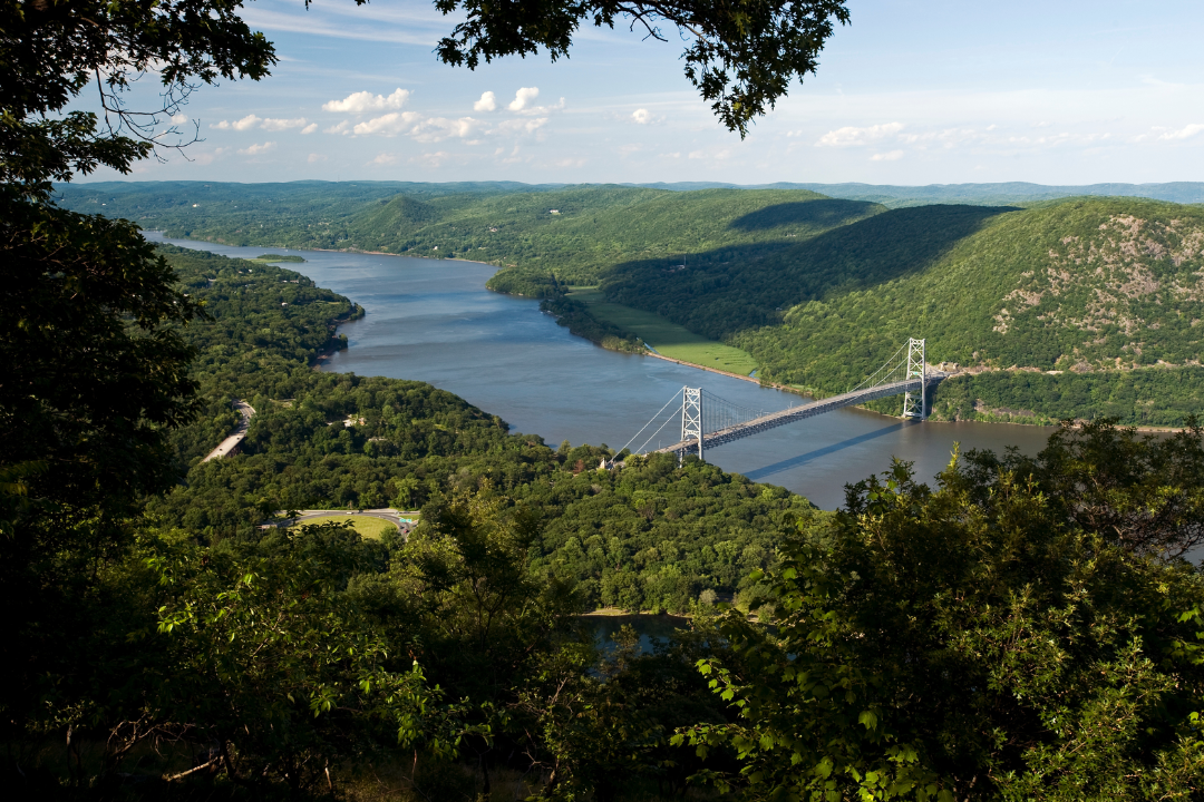 Overhead view of Bear Mountain Park, with tree-covered mountains, a river and a bridge shown.