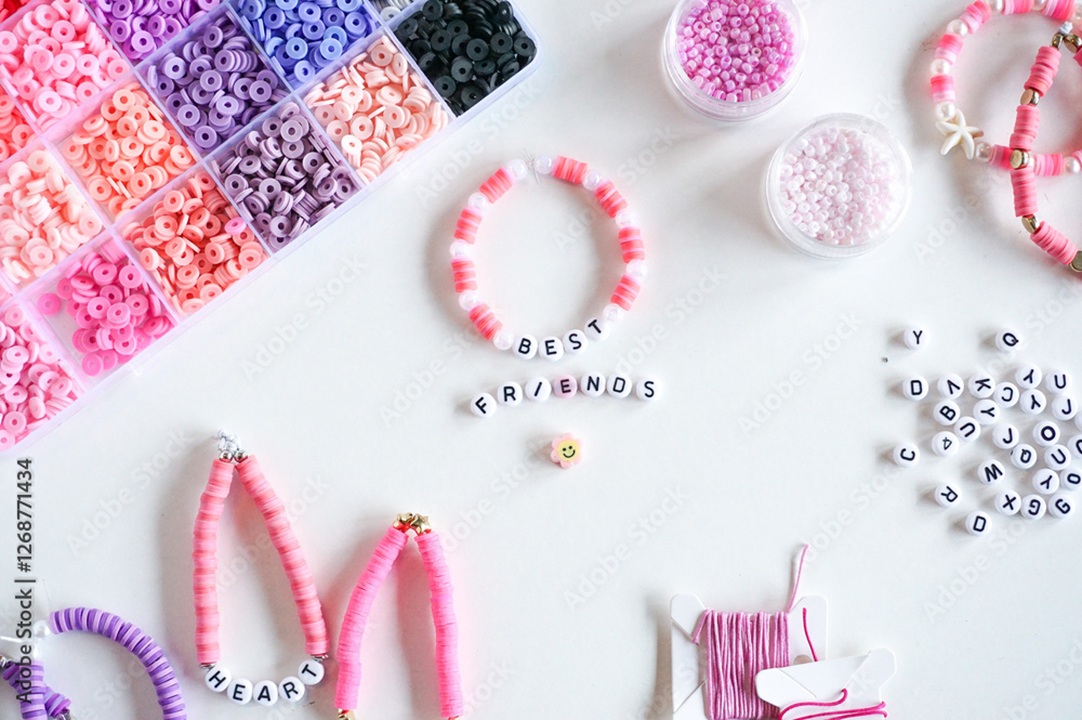 Photo of a few friendship bracelets and a tray of beads for making the bracelets. Beads are in pink and purple hues.