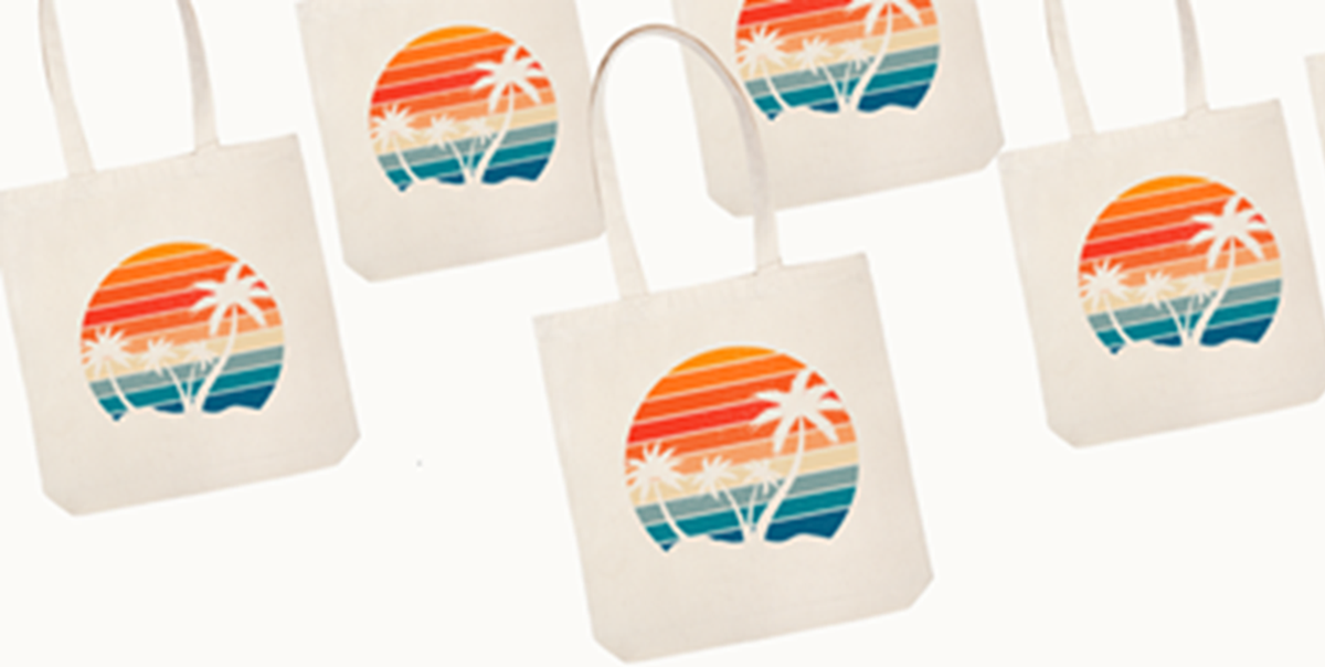 image of 5 off white canvas tote bags with a tropical image screenprinted on it. Palm trees, ocean, sand and sunny sky are part of tropical image.