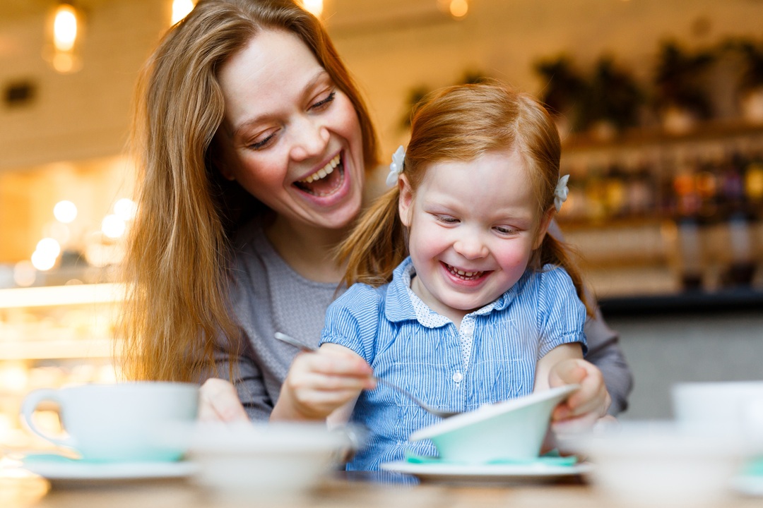 Photo of a mom and daughter laughing and enjoying a snack together in a cafeteria