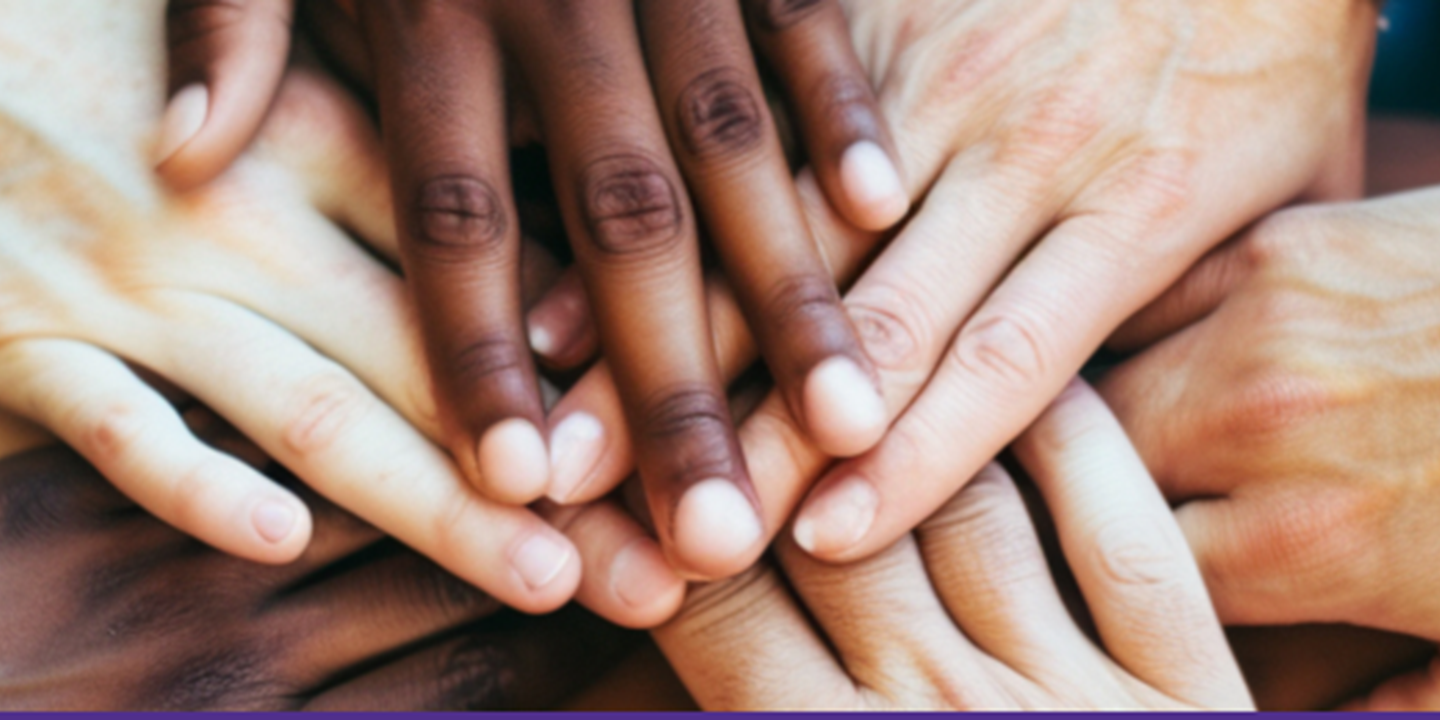 Photo of multiple hands laying on top of one another, providing support