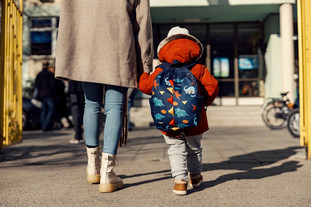 Photo of a woman and her child walking away from camera toward school