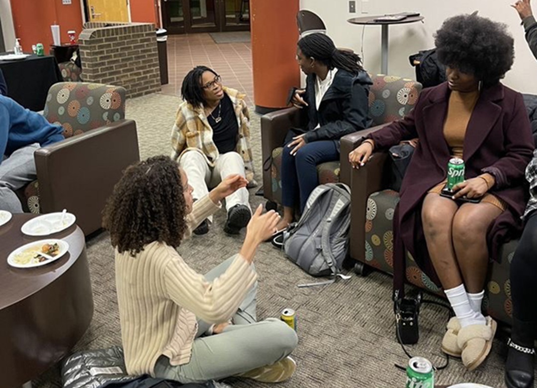 Photo of Council for Black Graduate students sitting and chatting in a lobby space.
