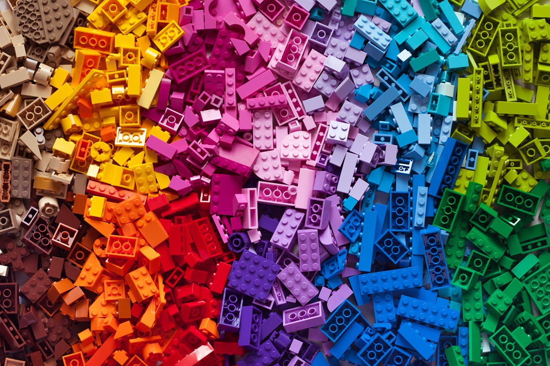 Photo of multi-colored LEGOs spread out on a table and grouped by color