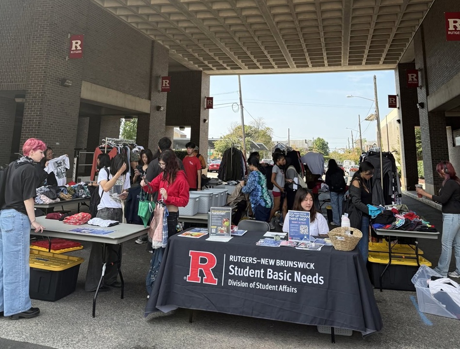 Photo of students shopping at a pop up thrift shop next to the student center on College Ave. Tables are set up with bins of clothing items for sale