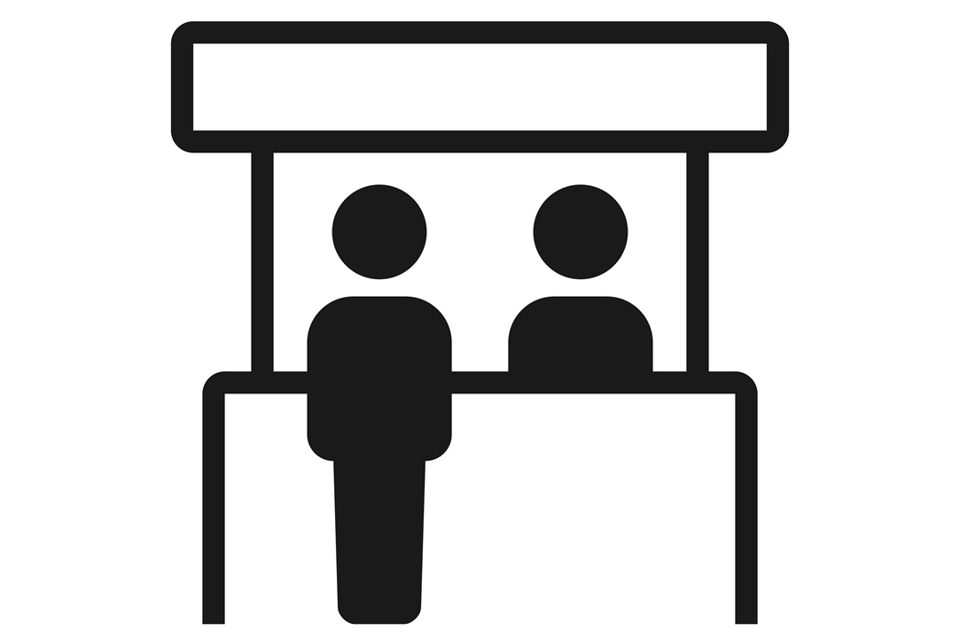 Black and white outline image of a person behind an information booth, with another person in front of it.